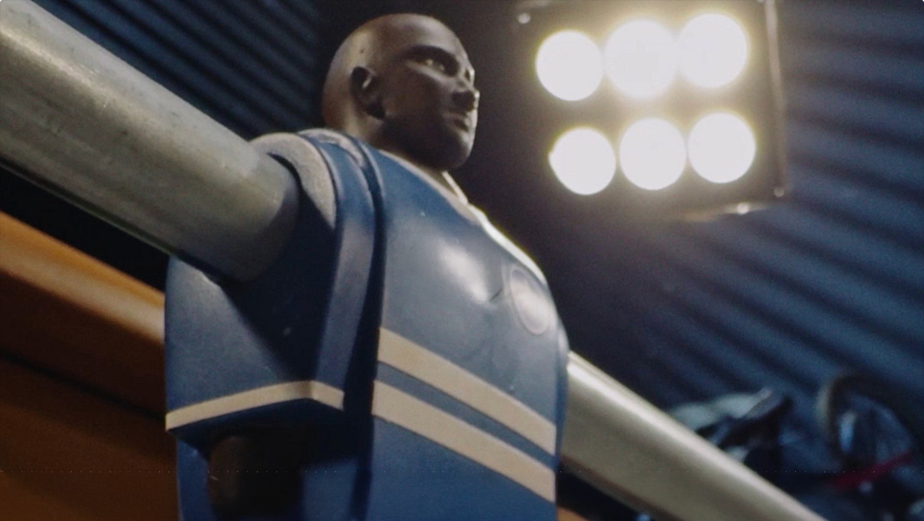 Red and blue foosball figures facing the ball in Apple Tiny Rivals, a vertical film by LOBO