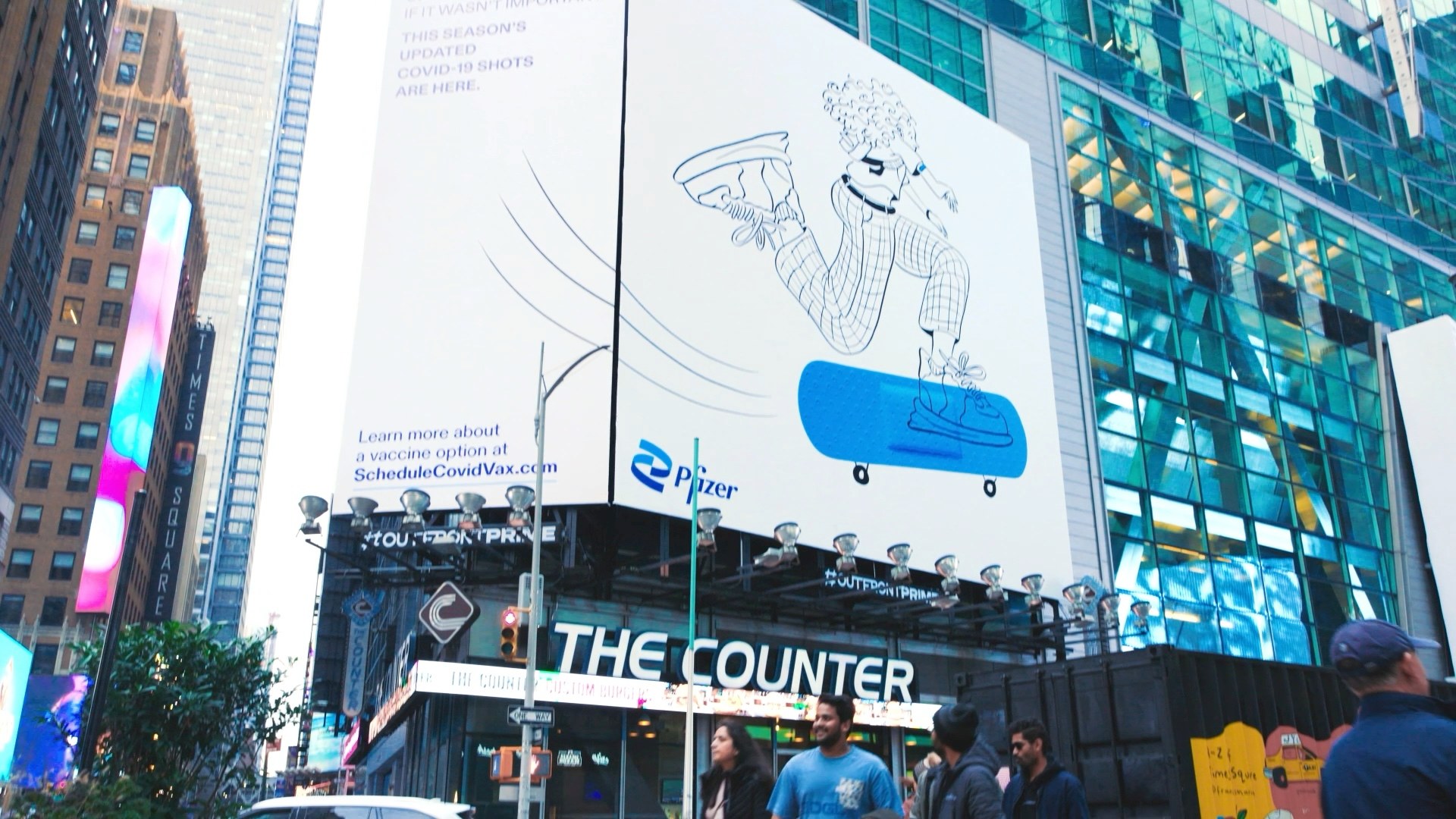 A street level Pfizer Doodles billboard above a diner called The Counter