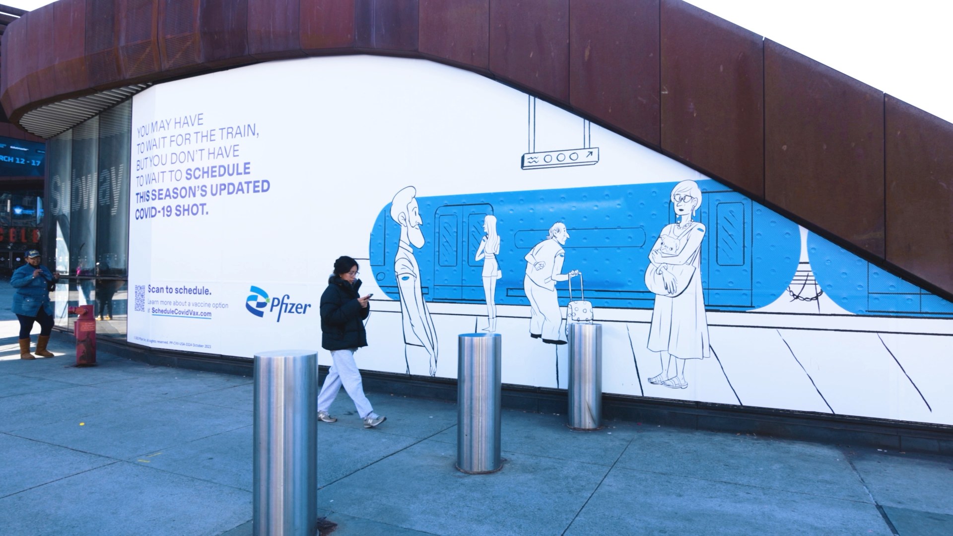 A subway wall wrapped end to end with the Pfizer Doodles artwork
