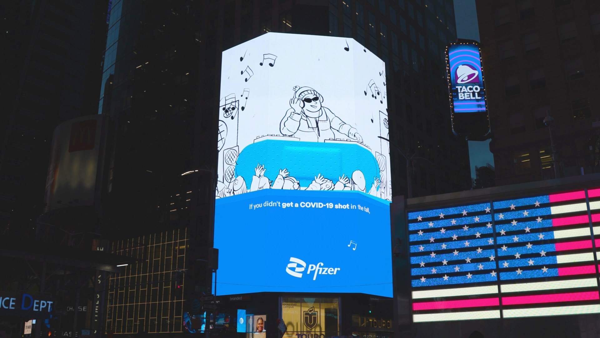 The Pfizer Doodles billboard lit blue in Times Square at night