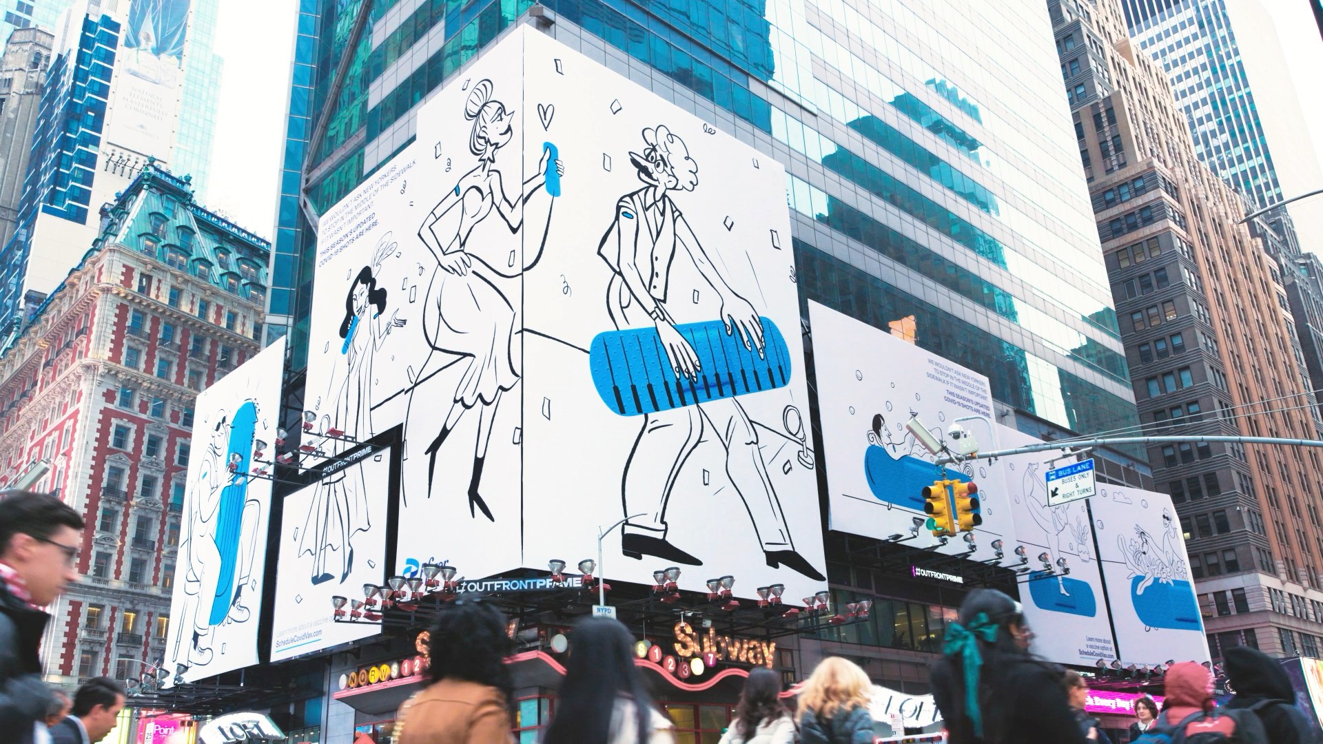 Pedestrians below the Pfizer Doodles screens in Times Square