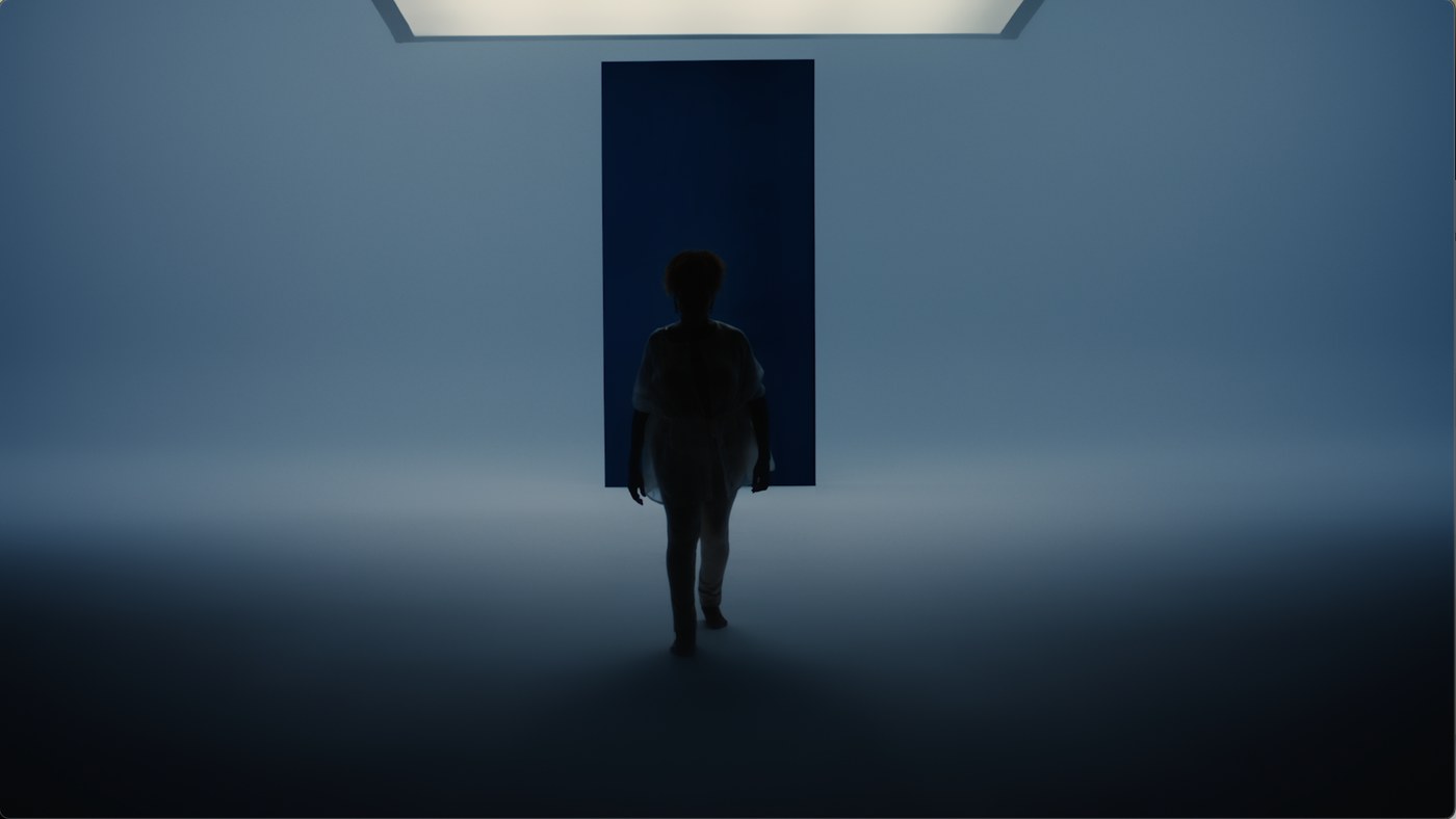 A figure walking away into a lit doorway at the end of the film