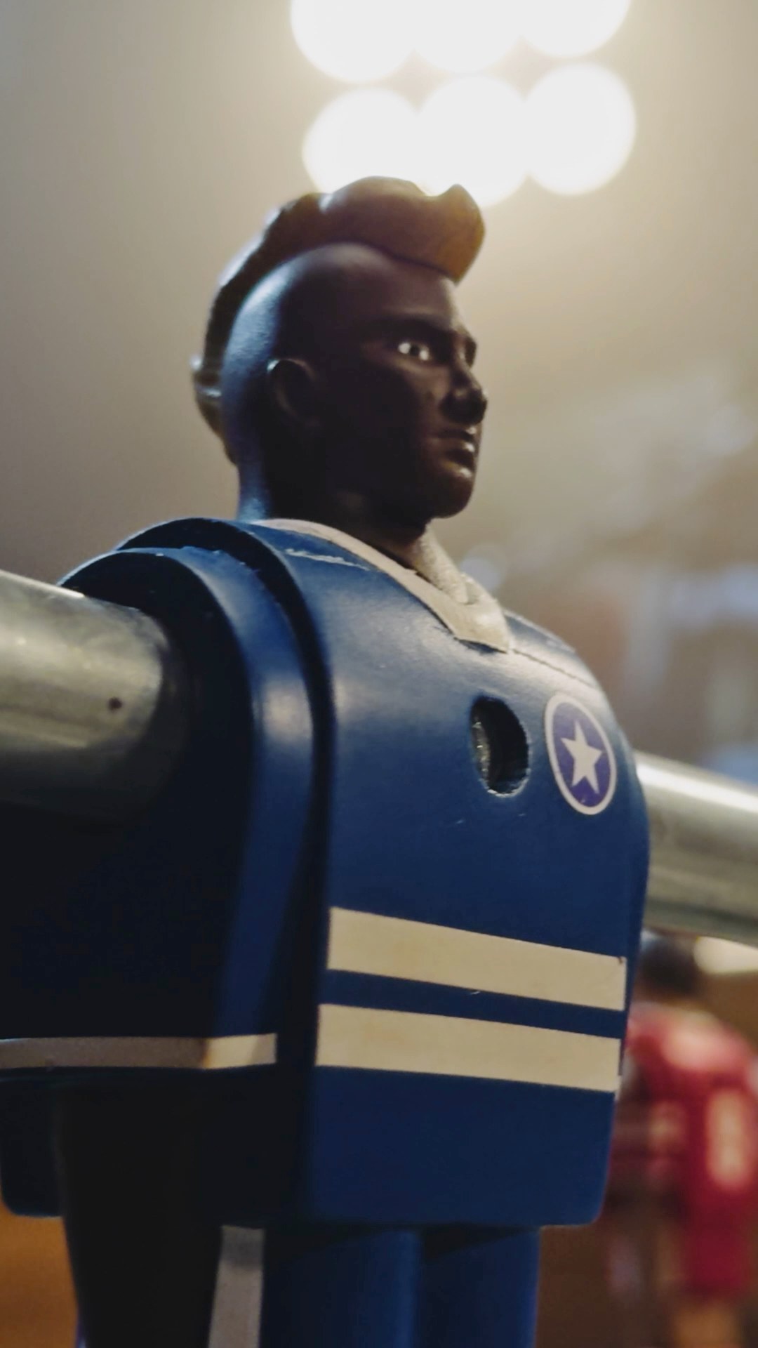 Red and blue foosball figures facing the ball in Apple Tiny Rivals, a vertical film by LOBO