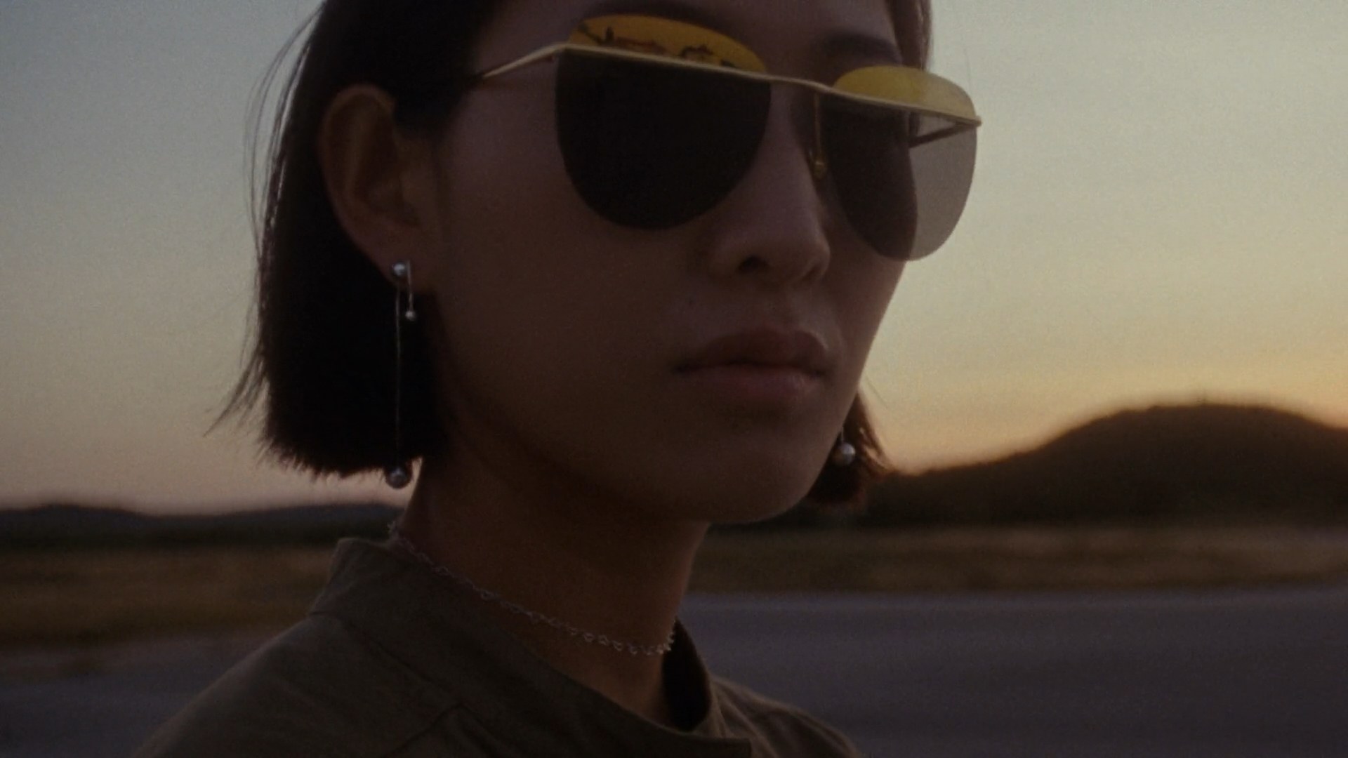 A woman in sunglasses at golden hour wearing Pandora jewellery